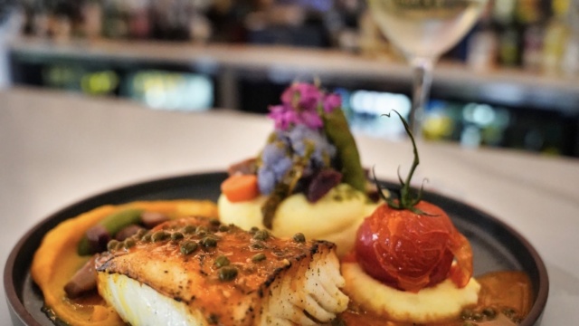 Fish entrée with vegetables and a glass of white wine at Acquario Italian Restaurant in Keller