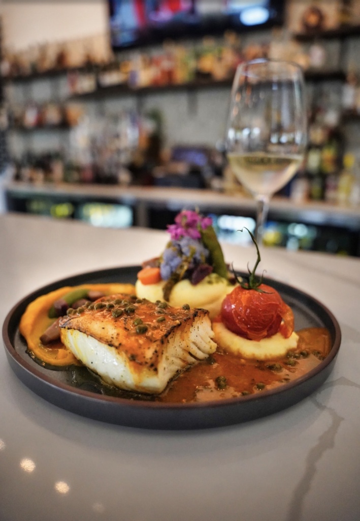 Fish entrée with vegetables and a glass of white wine at Acquario Italian Restaurant in Keller