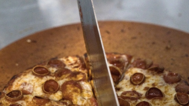 Pepperoni pizza being sliced at Mountain Mike’s Pizza in Keller