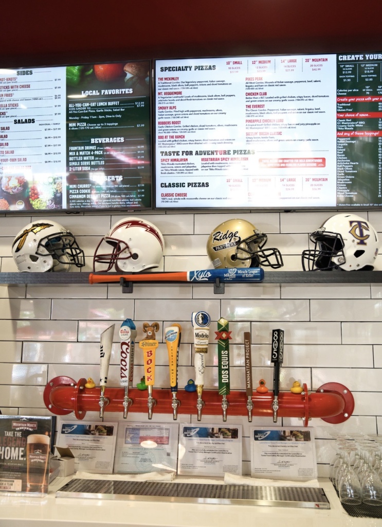 Local football helmets and beer taps beneath the menu at Mountain Mike’s Pizza in Keller